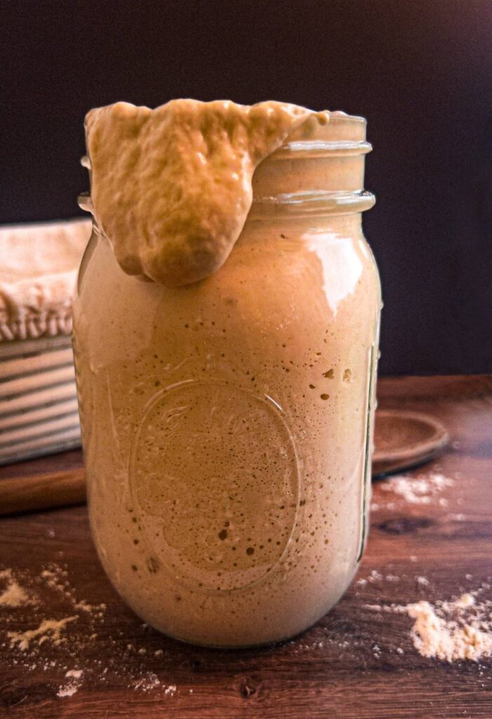 Sourdough starter falling out of a glass mason jar. Used for learning how to care for sourdough starter.