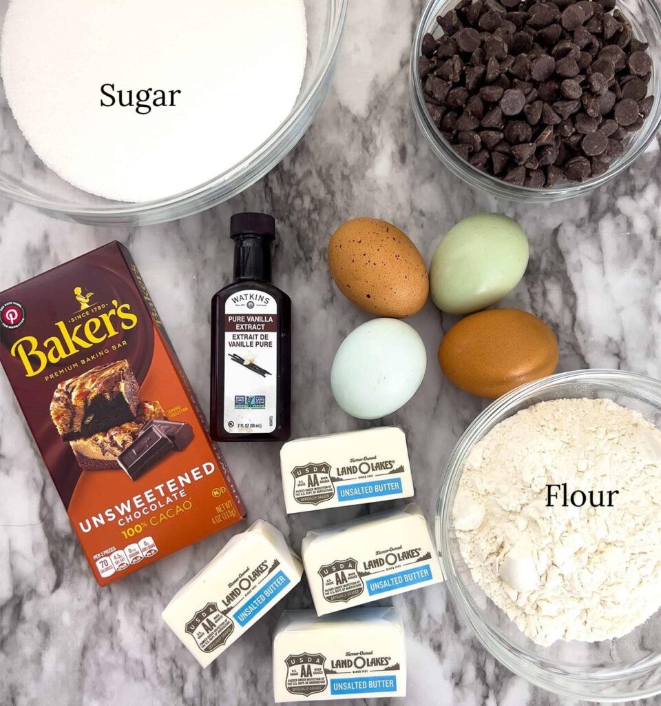 Chocolate, butter, vanilla, sugar and eggs on a countertop.