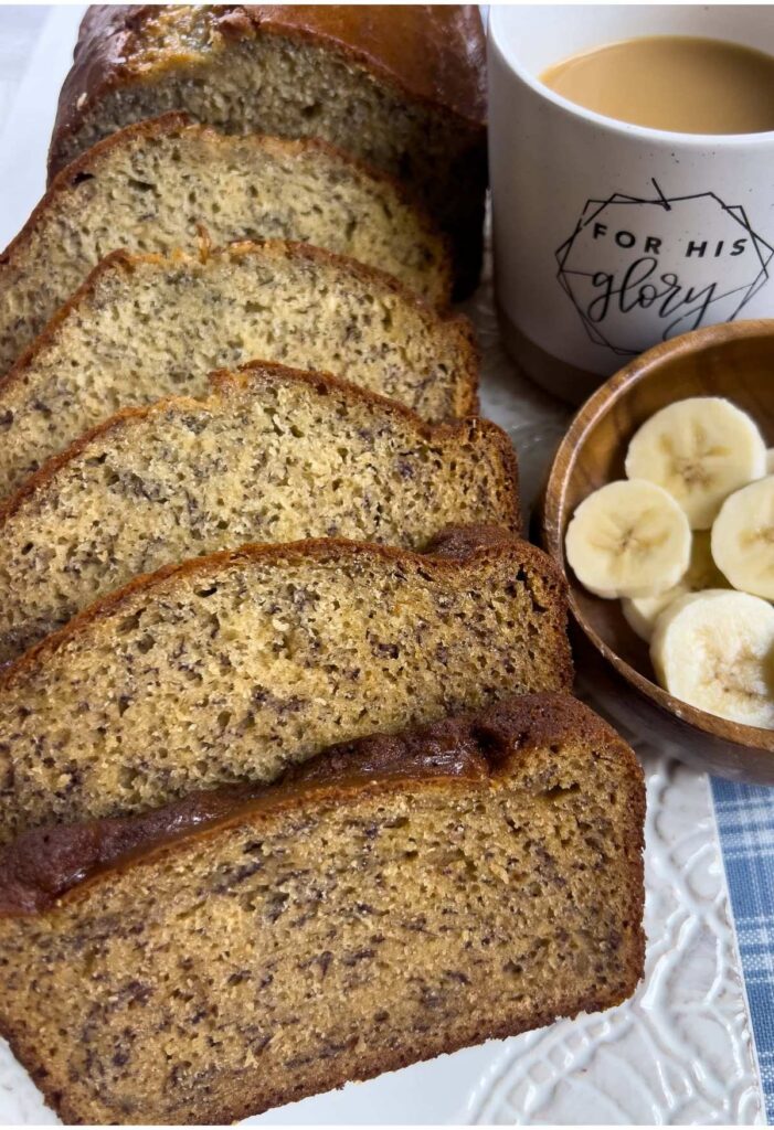 Slices of no oil banana bead on a white ceramic dish with coffee and banana slices on the right. 