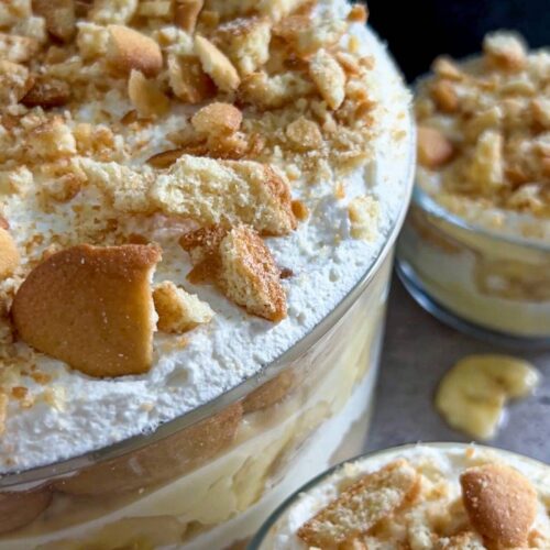 A trifle bowl of the best southern banana pudding with two individuals bowls next to it.