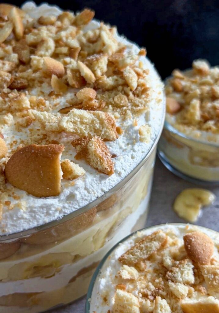 A trifle bowl of the best southern banana pudding with two individuals bowls next to it.