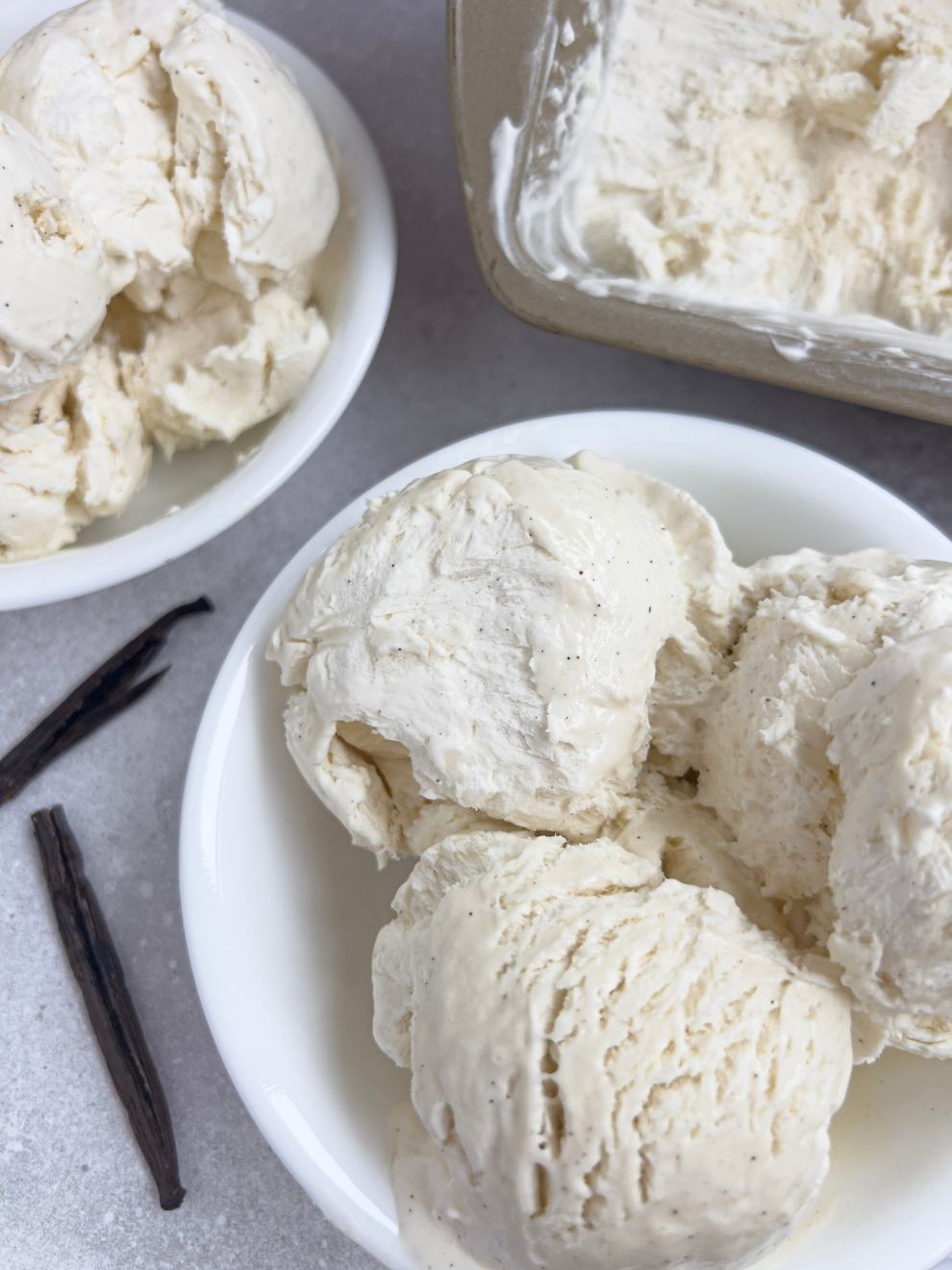 A bowl of three scoops of no churn vanilla bean ice cream. 