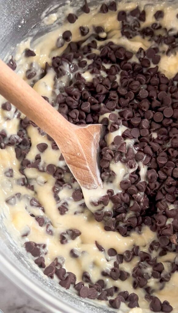 A closeup of banana bread batter with mini chocolate chips being folded in. 