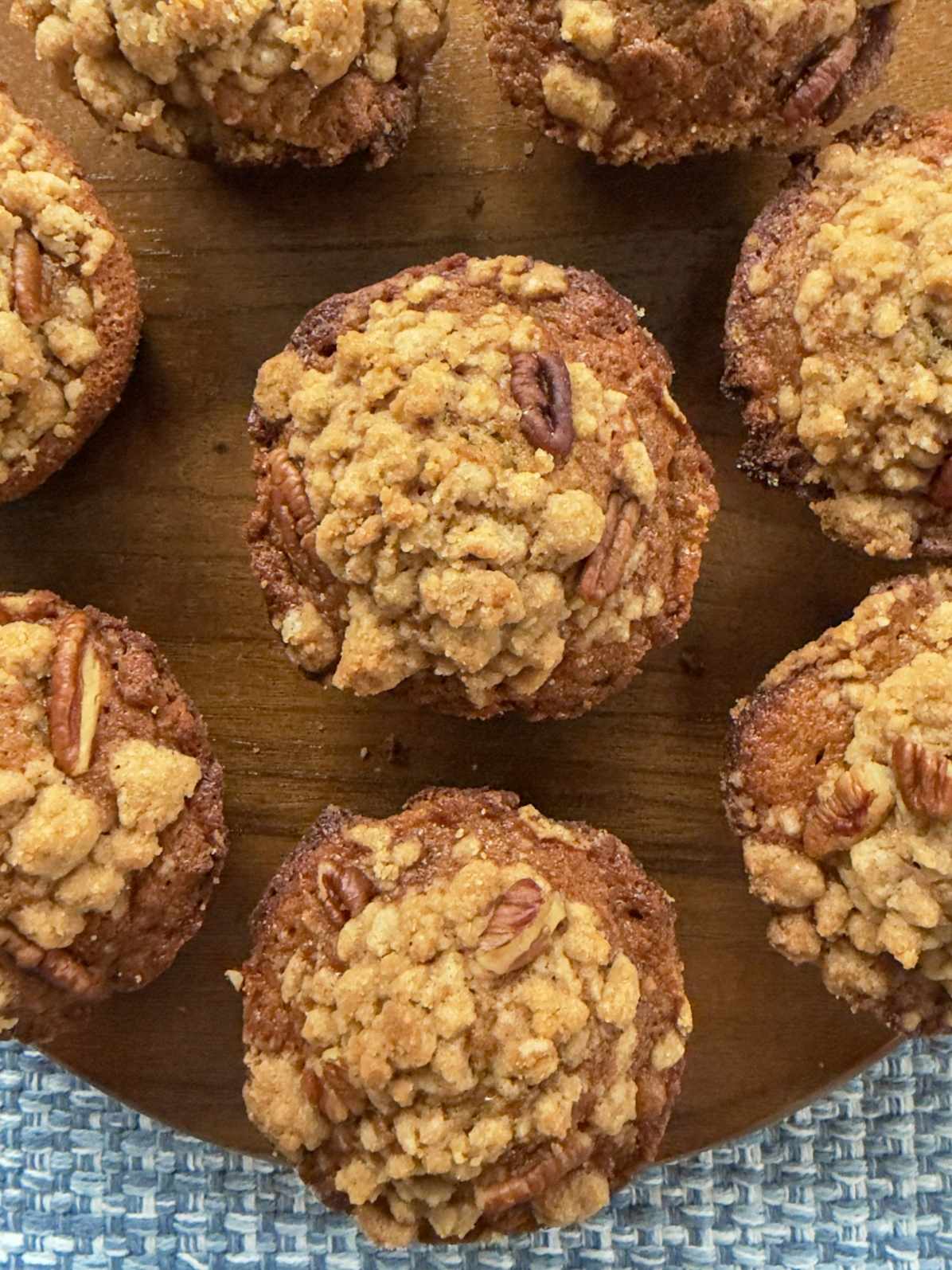 Six bakery style banana nut muffins on a wooden board.