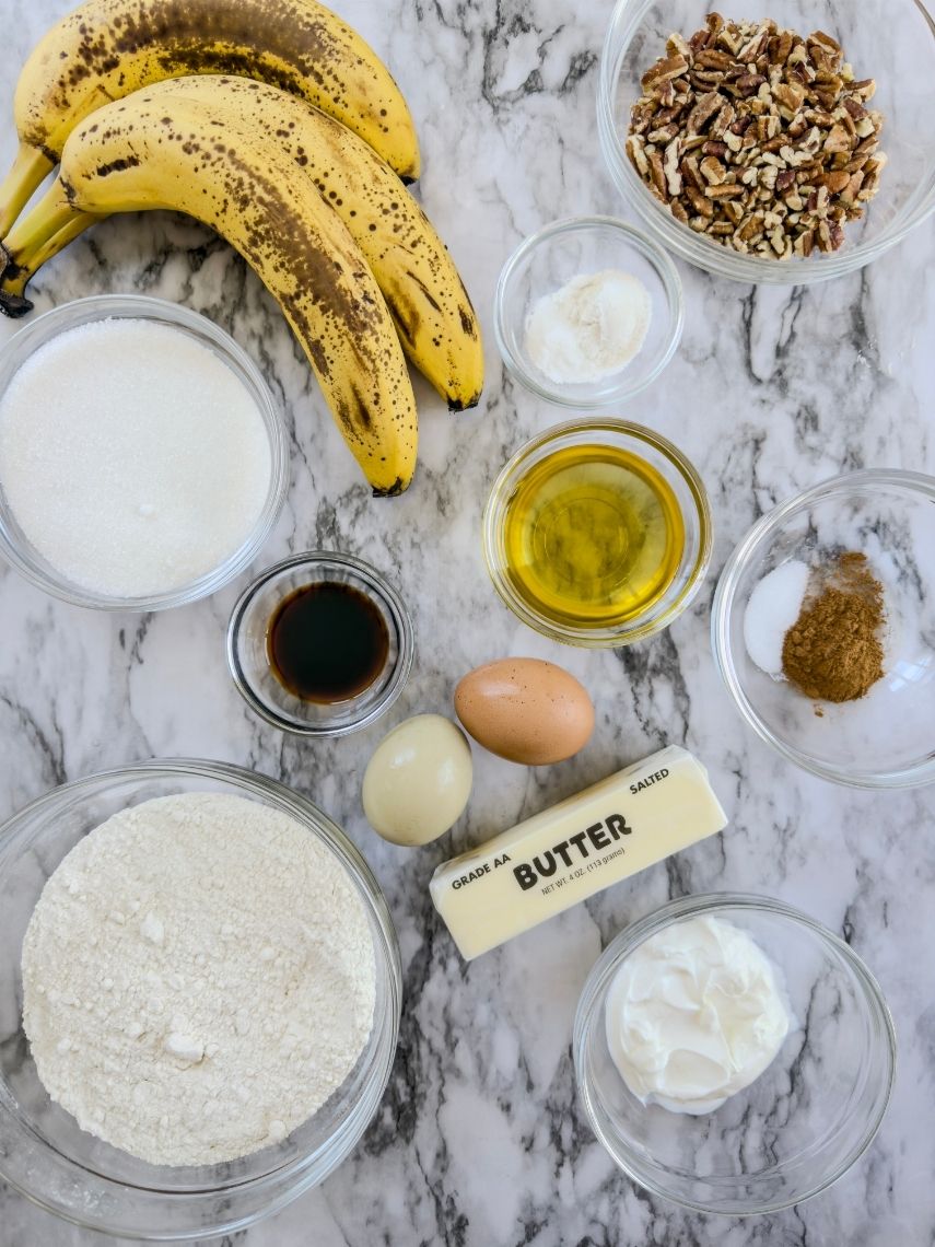 Ingredients for bakery style banana nut muffins on a marble countertop.