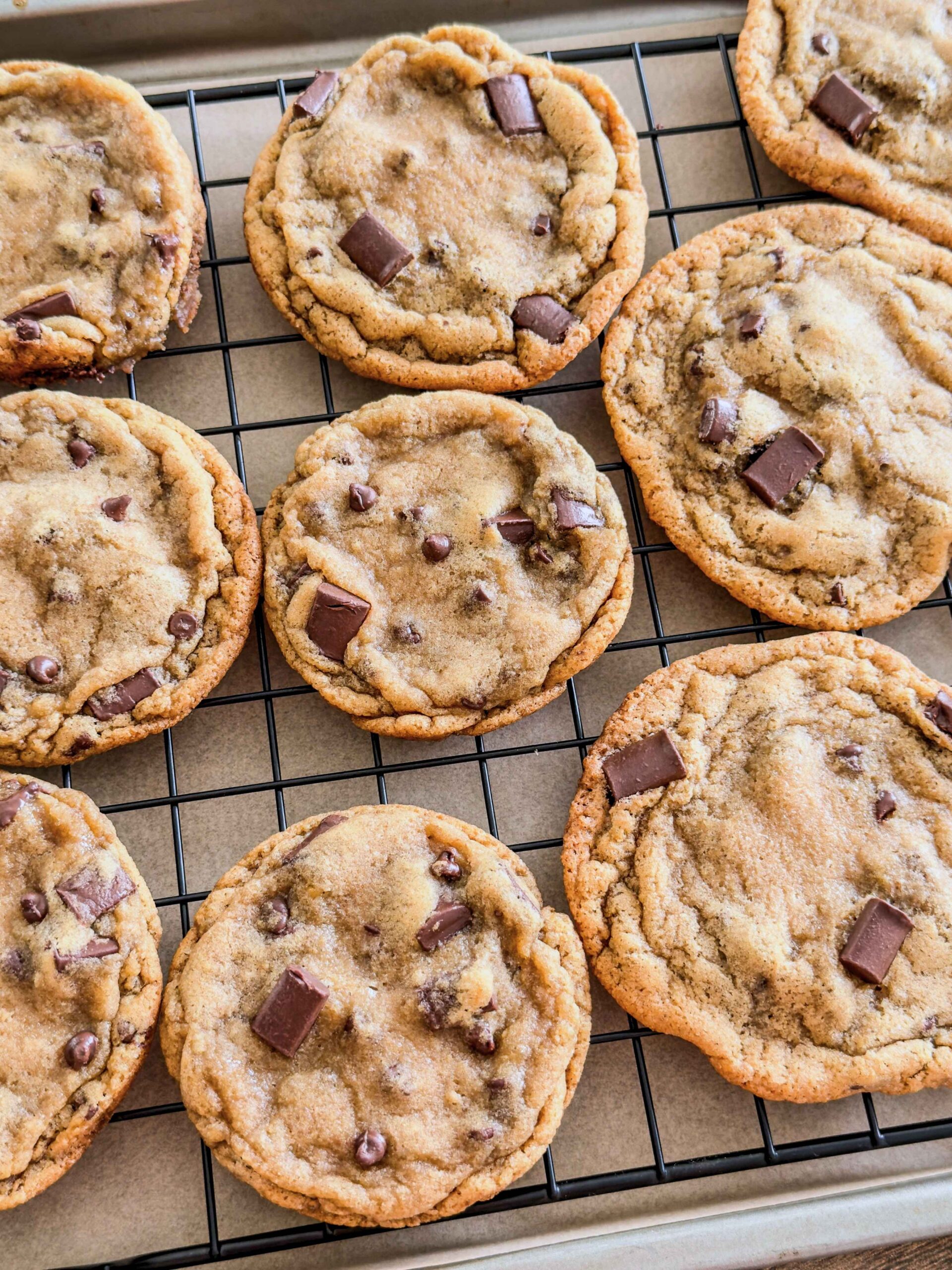 Several Magnolia style chocolate chip cookies on a baking rack