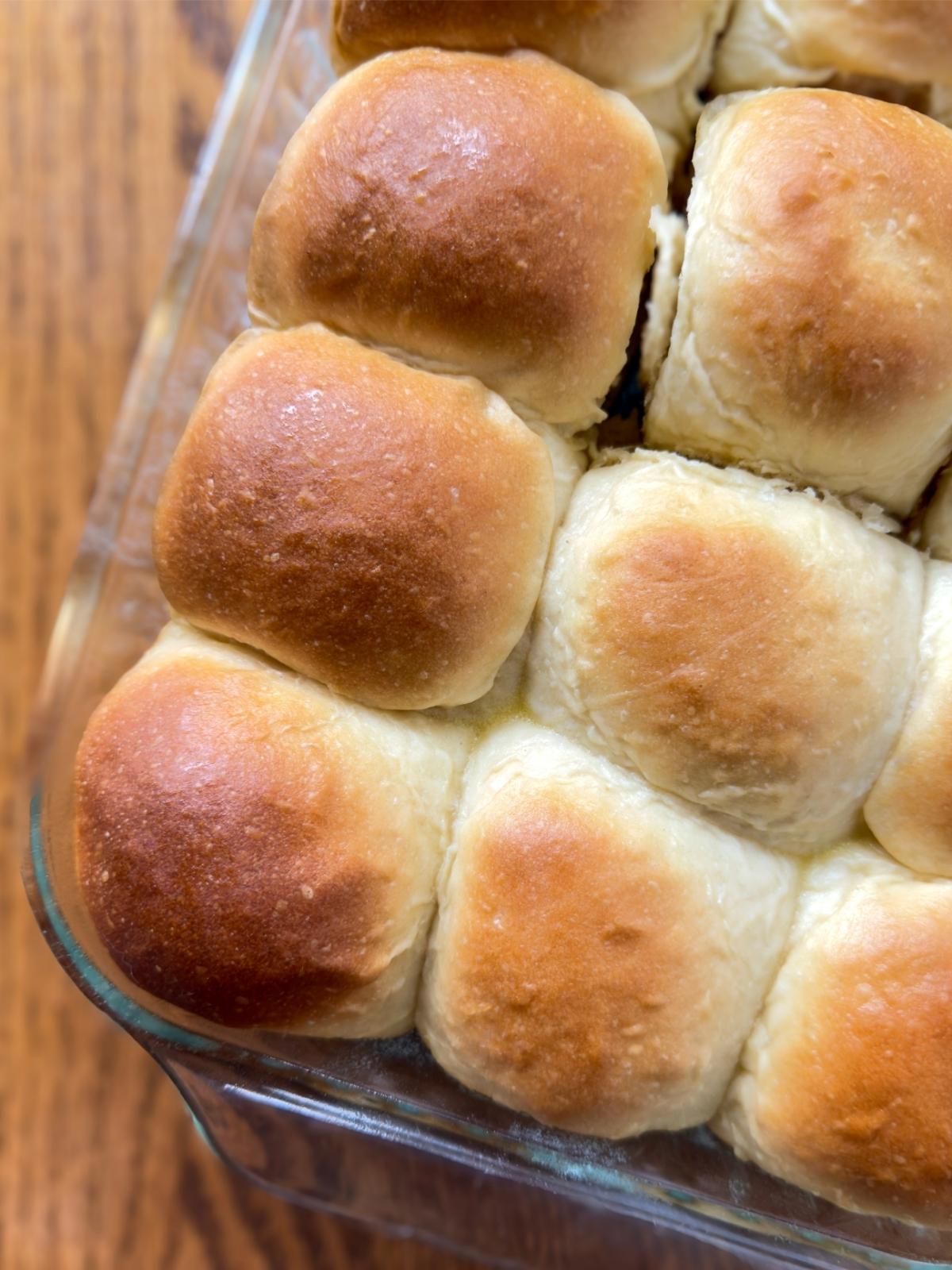 Soft & Fluffy Homemade Dinner Rolls in a glass dish on a wooden table.