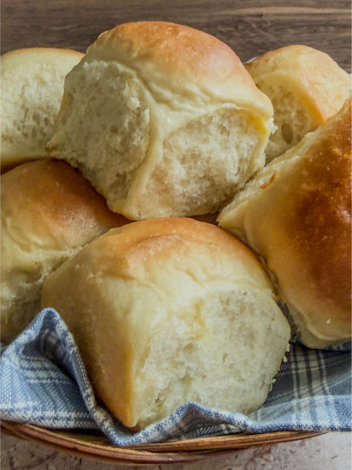 A basket of Soft & Fluffy Homemade Dinner Rolls in a blue cloth napkin.