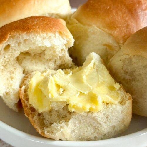 Soft & Fluffy Homemade Dinner Rolls on a plate with butter.