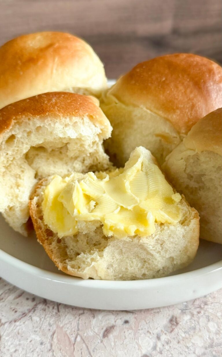 Soft & Fluffy Homemade Dinner Rolls on a plate with butter.