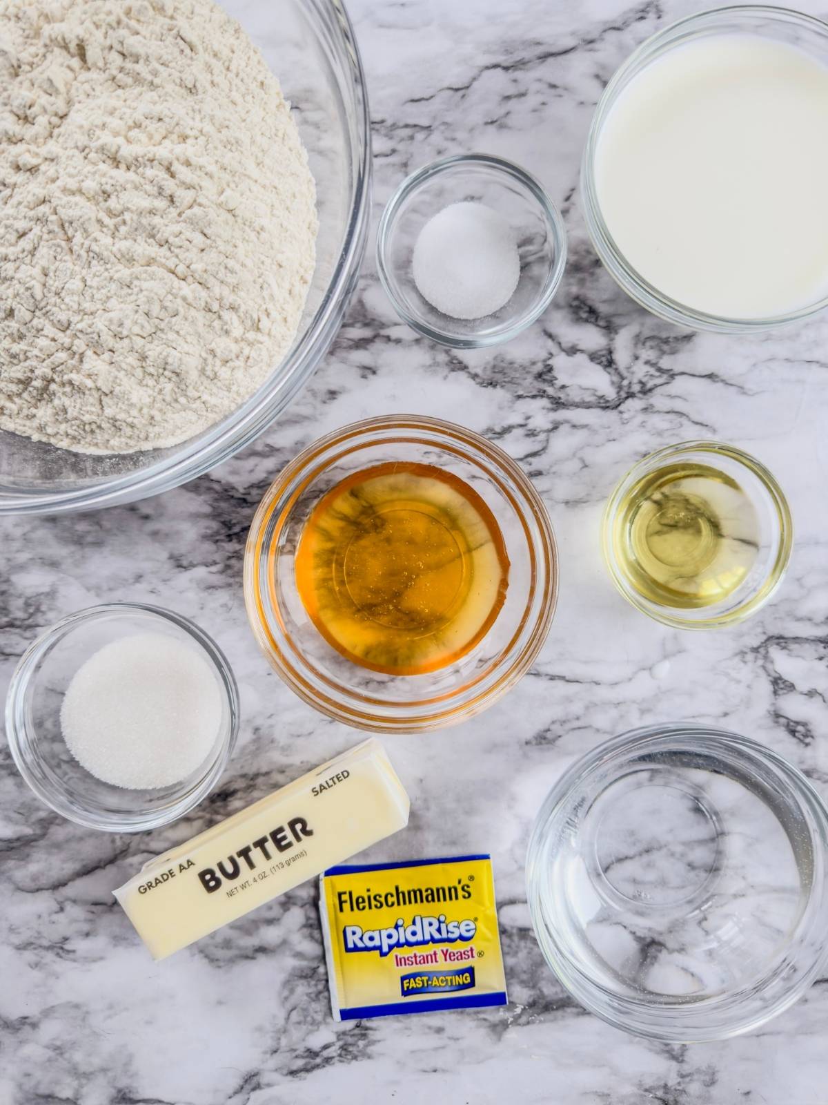 Ingredients for Soft & Fluffy Homemade Dinner Rolls on a marbled countertop.